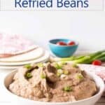 A bowl filled with refried beans topped with green scallions.