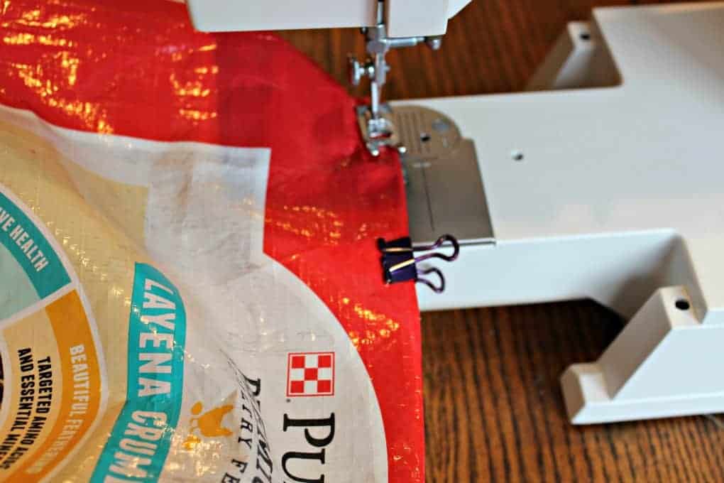 Sewing the top hem of a feed bag with a sewing machine.