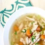 A bowl of chicken soup with carrots and small pasta.