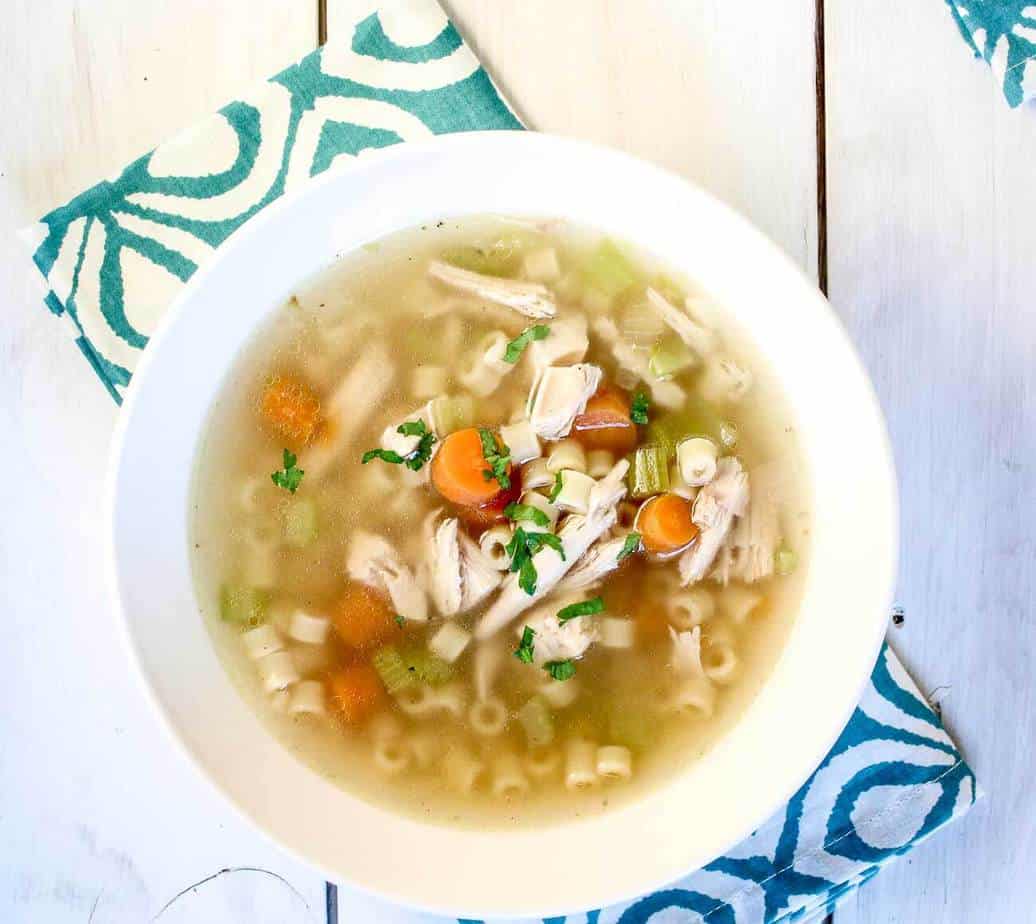 A white bowl filled with soup sitting on a patterned napkin.