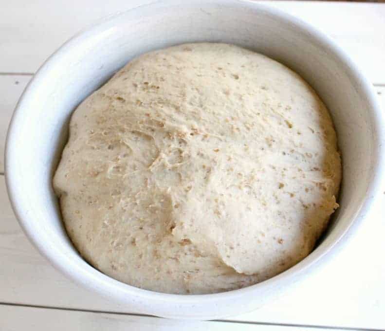 Bread dough rising in a large white bowl.
