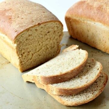 Two loaves of homemade bread with one loaf partially sliced.