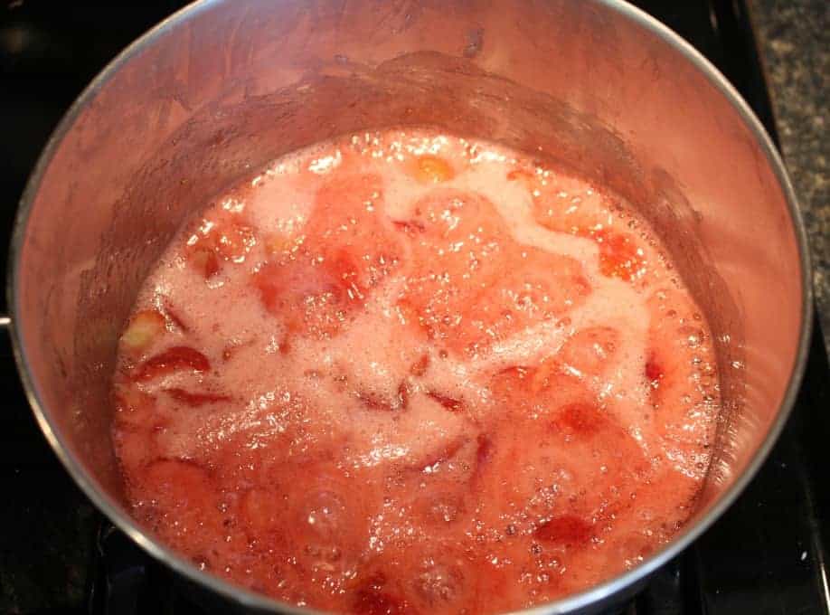 Cooking strawberry jam in a large pot.