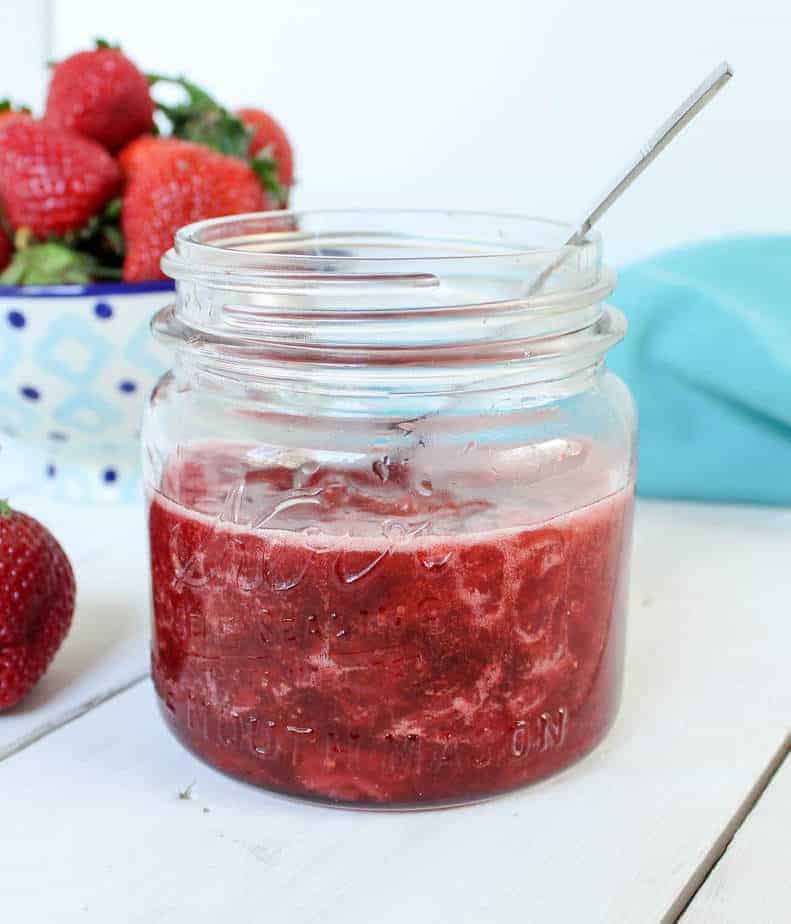 A canning jar filled with red jam. 