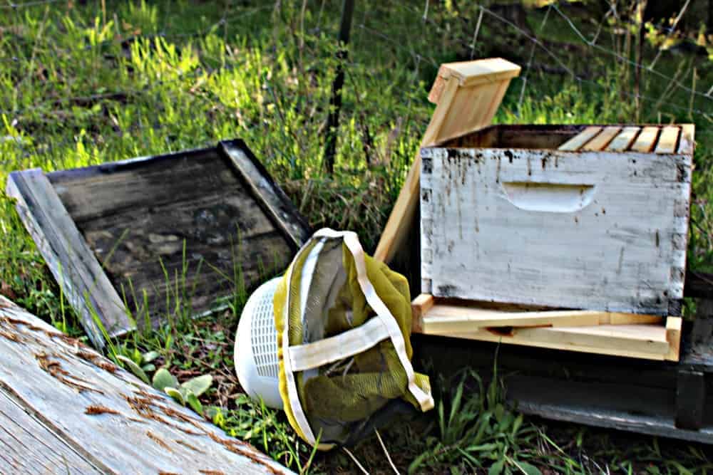A wooden hive with the lid off and a bee hat and veil next to the box.