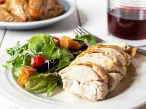 Sliced chicken breasts on a plate with a salad.