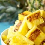 Chunks of grilled pineapple in a small white bowl.
