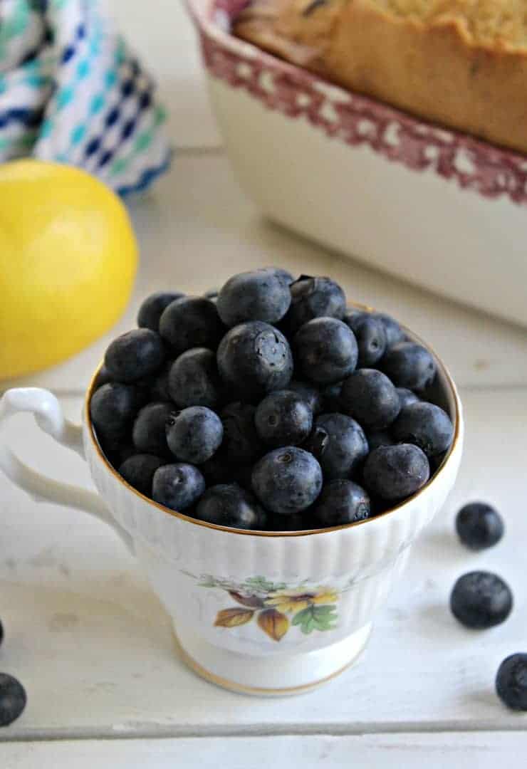 A china tea cup filled with fresh blueberries.