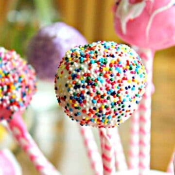 Round balls of cake stuck on a colorful stick and covered with a candy coating.