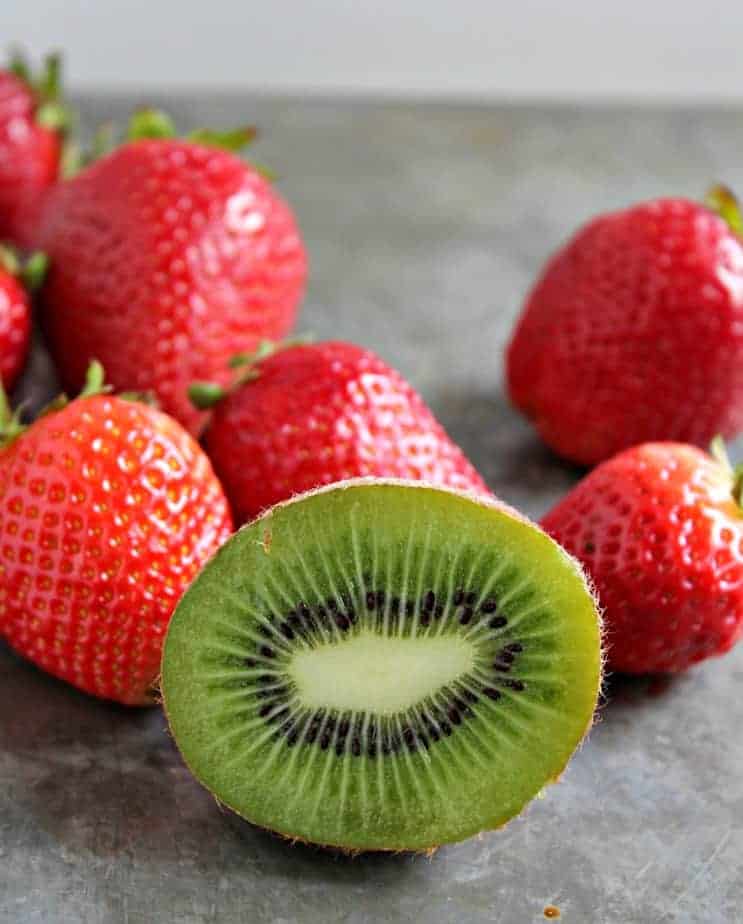 Fresh strawberries and kiwis on a gray surface.
