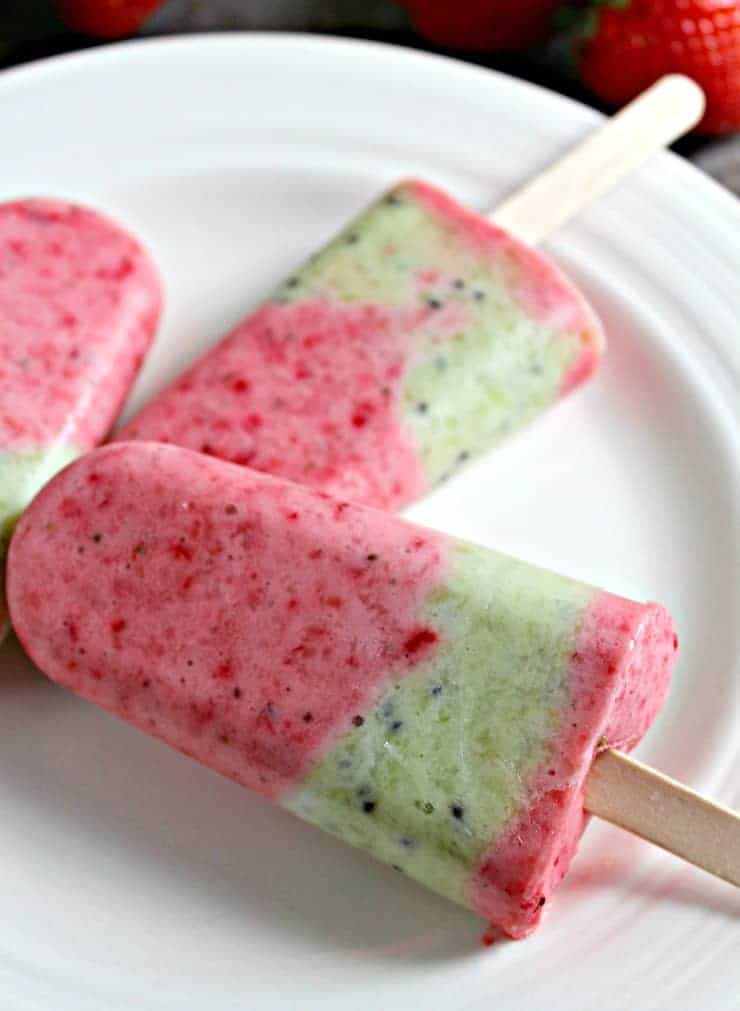 A plate with red and green frozen popsicles on the plate.