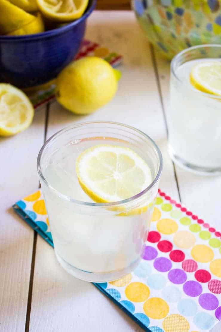 A glass filled with lemonade with a lemon slice floating on top. 