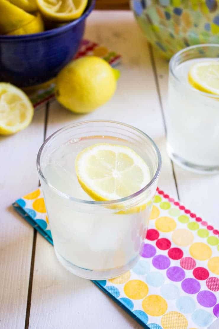 A glass filled with lemonade with a lemon slice floating on top.
