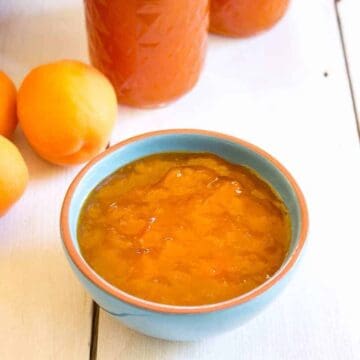 A small turquoise bowl filled with apricot jam.