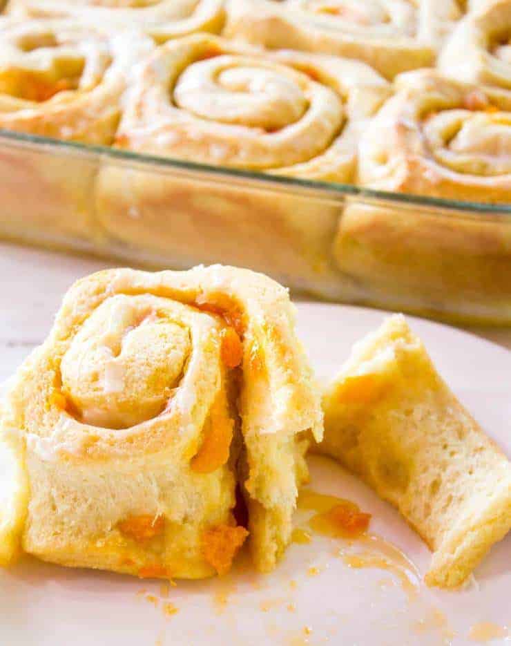 A sweet roll filled with apricots on a white plate.
