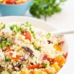 Couscous and fresh veggies in a white bowl with a spoon.