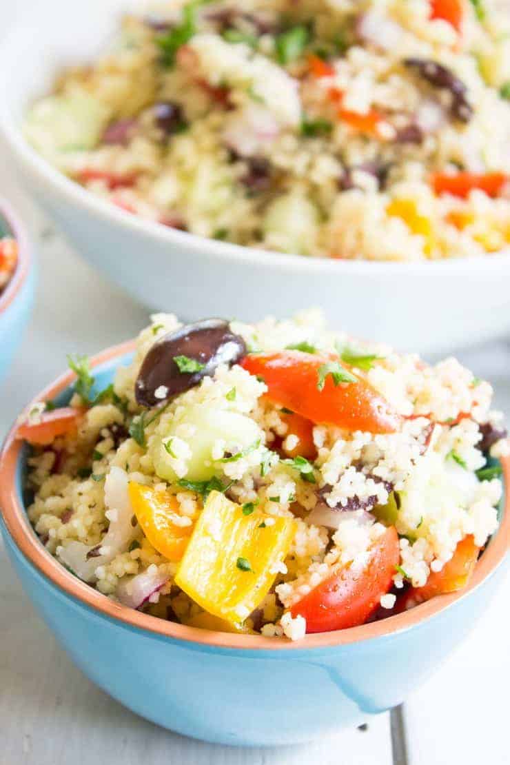 A blue bowl filled with peppers, onions, tomatoes, cucumbers and couscous.