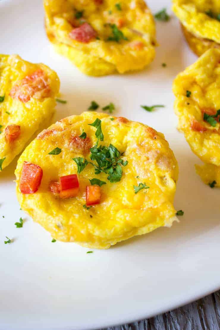Egg cups topped with fresh parsley and chopped red bell peppers. 