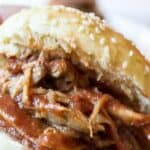 A sandwich bun filled with pulled pork with barbecue sauce.