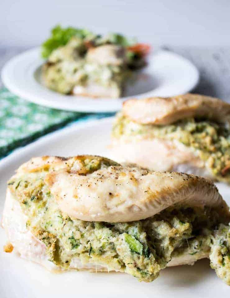 Zucchini stuffed chicken breasts on a white plate. 