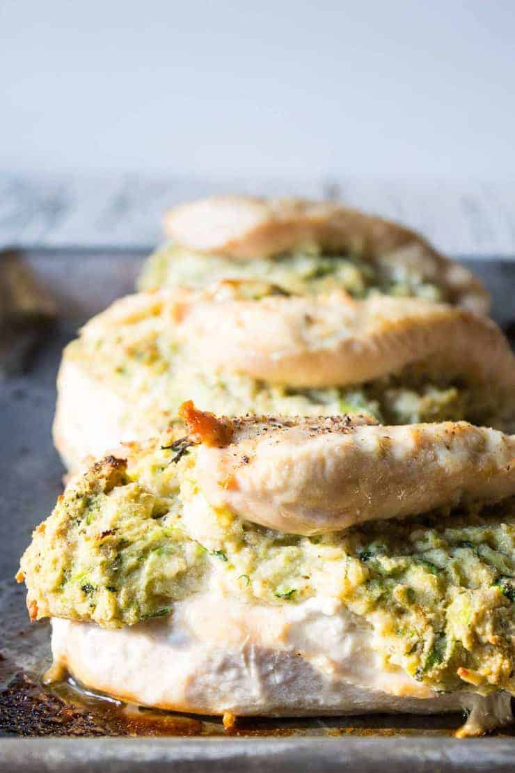 Baked chicken on a baking sheet with a stuffing inside the chicken.