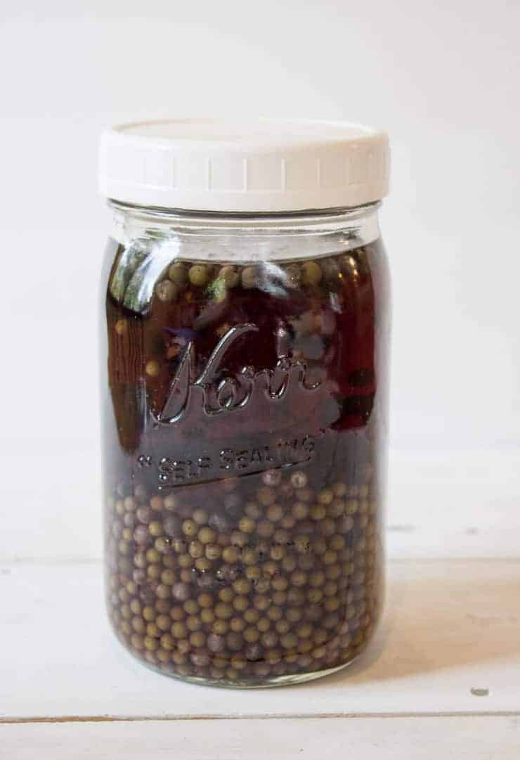 A jar filled with small berries in a liquid.