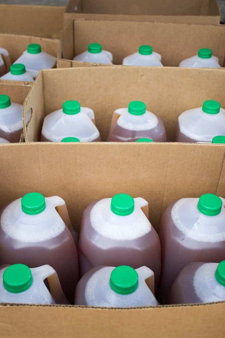 Cider in gallon jugs stacked in boxes. 