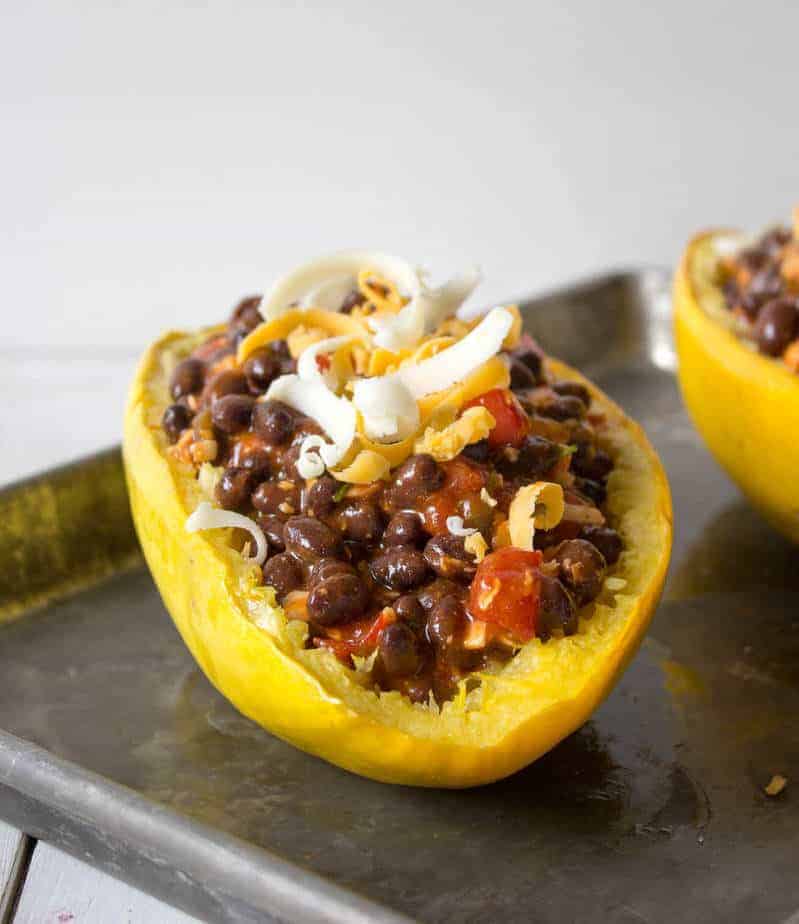 Spaghetti squash cut in half and filled with black beans and  topped with cheese.