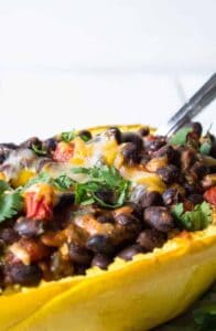 Half a spaghetti squash shell filled with black beans, tomatoes and cheese.