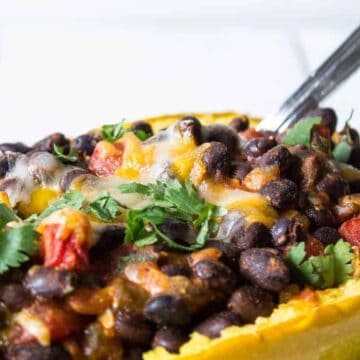 Half a spaghetti squash shell filled with black beans, tomatoes and cheese.