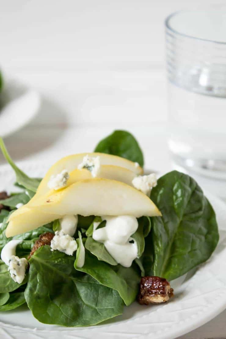 Spinach, Pear and Blue Cheese Salad topped with pecans and blue cheese crumbles.