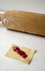 A small layer of raspberry jam on a square of cookie dough.