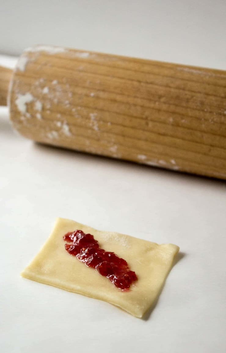 A small layer of raspberry jam on a square of cookie dough.