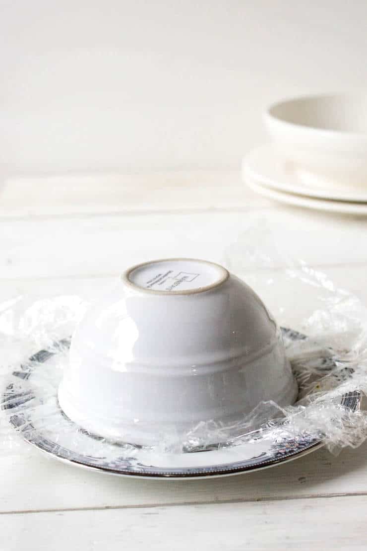 A small white bowl placed upside down on a plate.