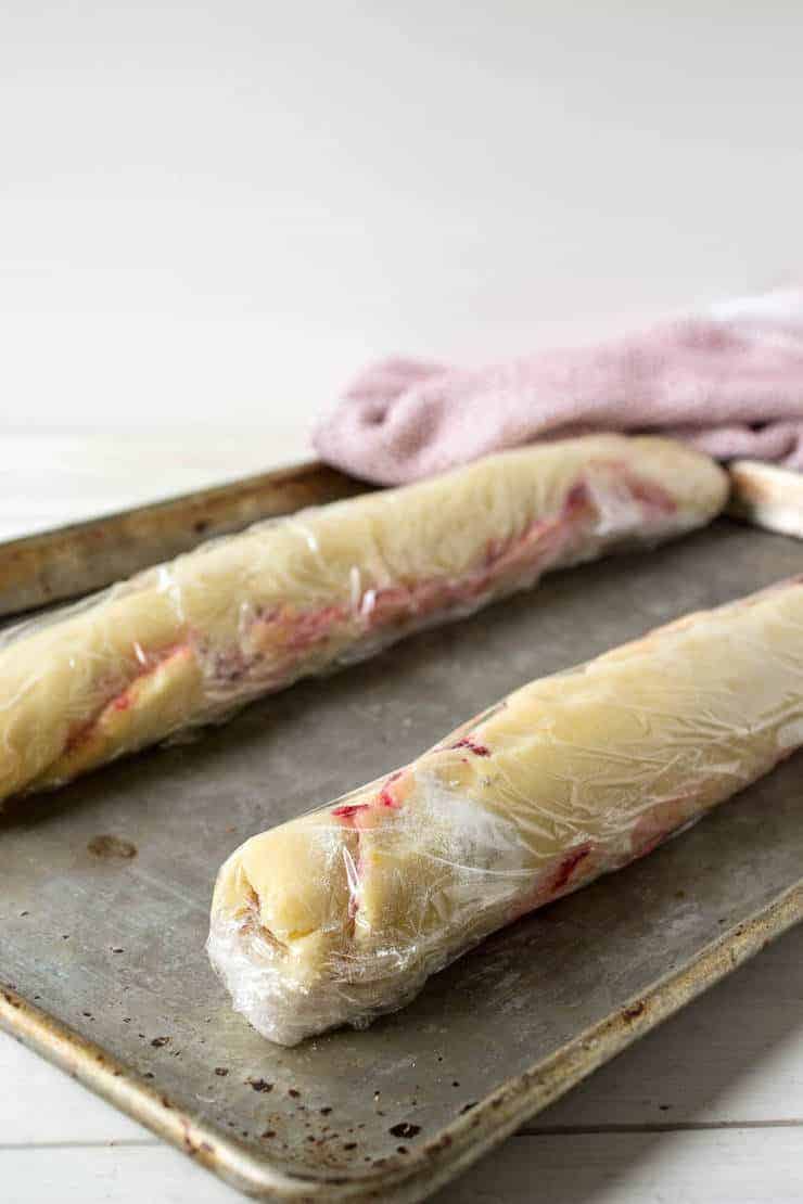 Cookie dough logs wrapped in plastic wrap.