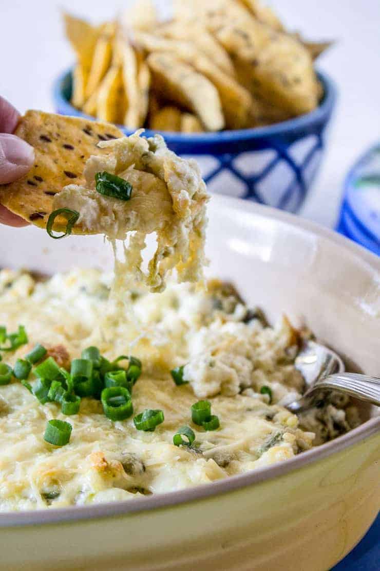 A tortilla chip scooping up cheesy jalapeno popper dip.