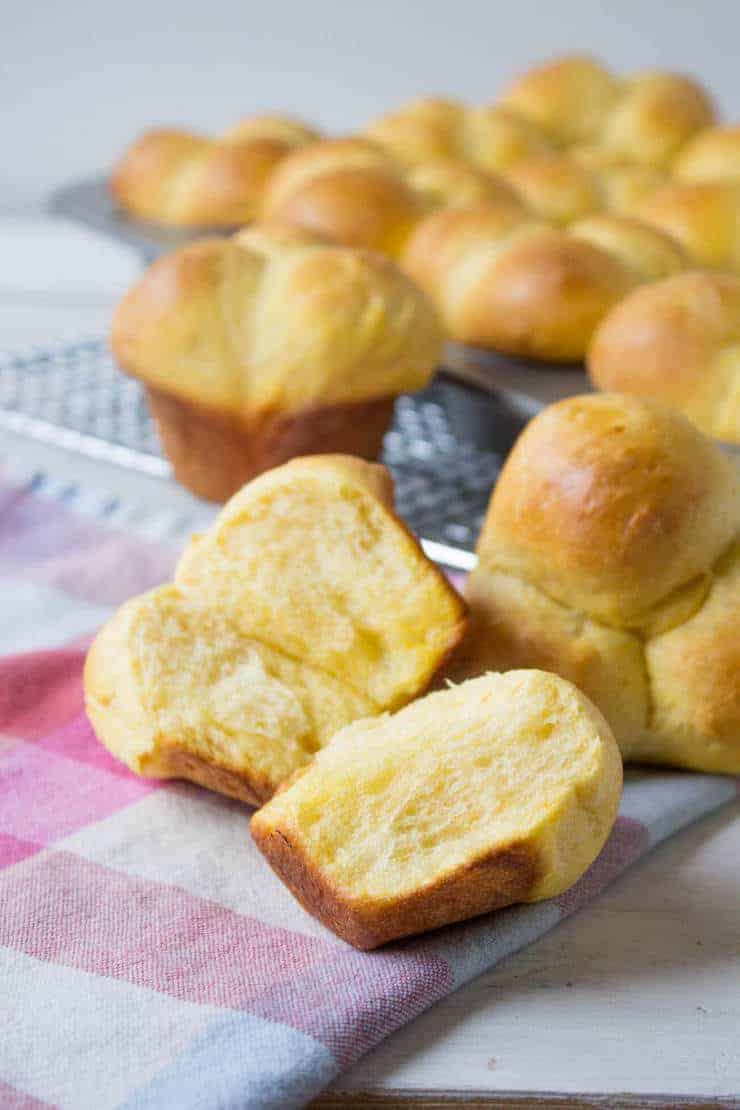 Sweet Potato Dinner Rolls cut in half and resting on a cooling rack. 