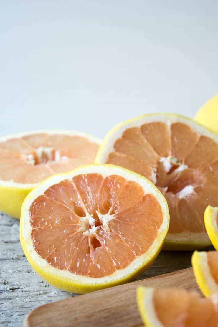 Fresh grapefruit sliced in half and sitting on a gray counter.