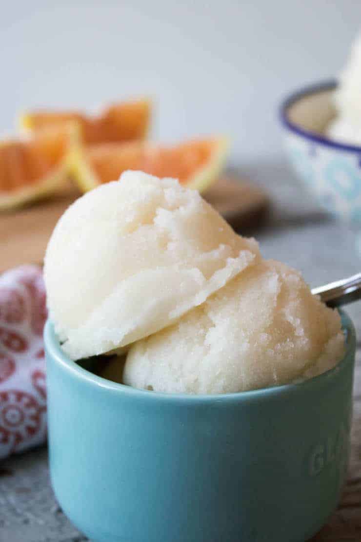 Two scoops of a white colored frozen treat in a turquoise bowl.