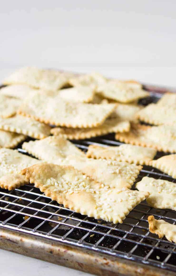 Long crackers topped with sesame seeds resting on a baking rack.