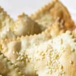 A bowl filled with rustic shaped crackers topped with sesame seeds.
