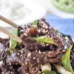 Strips of cooked meat topped with sesame seeds and chopped green onions.