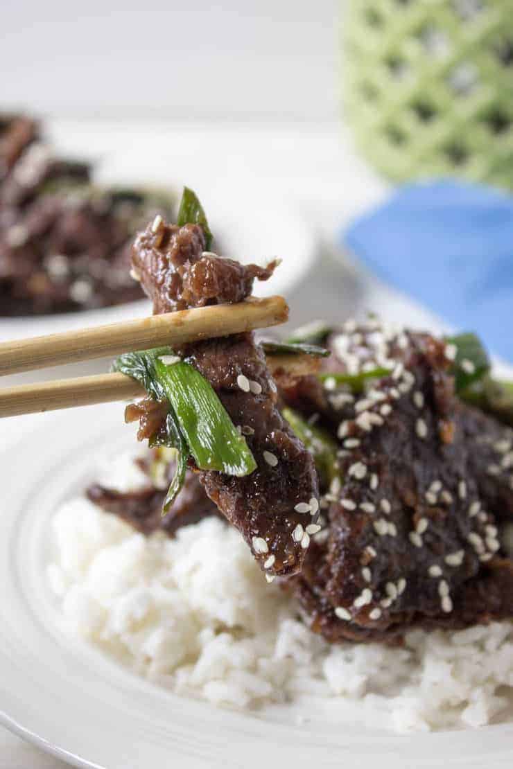 Chopsticks picking up a bit of cooked meat.