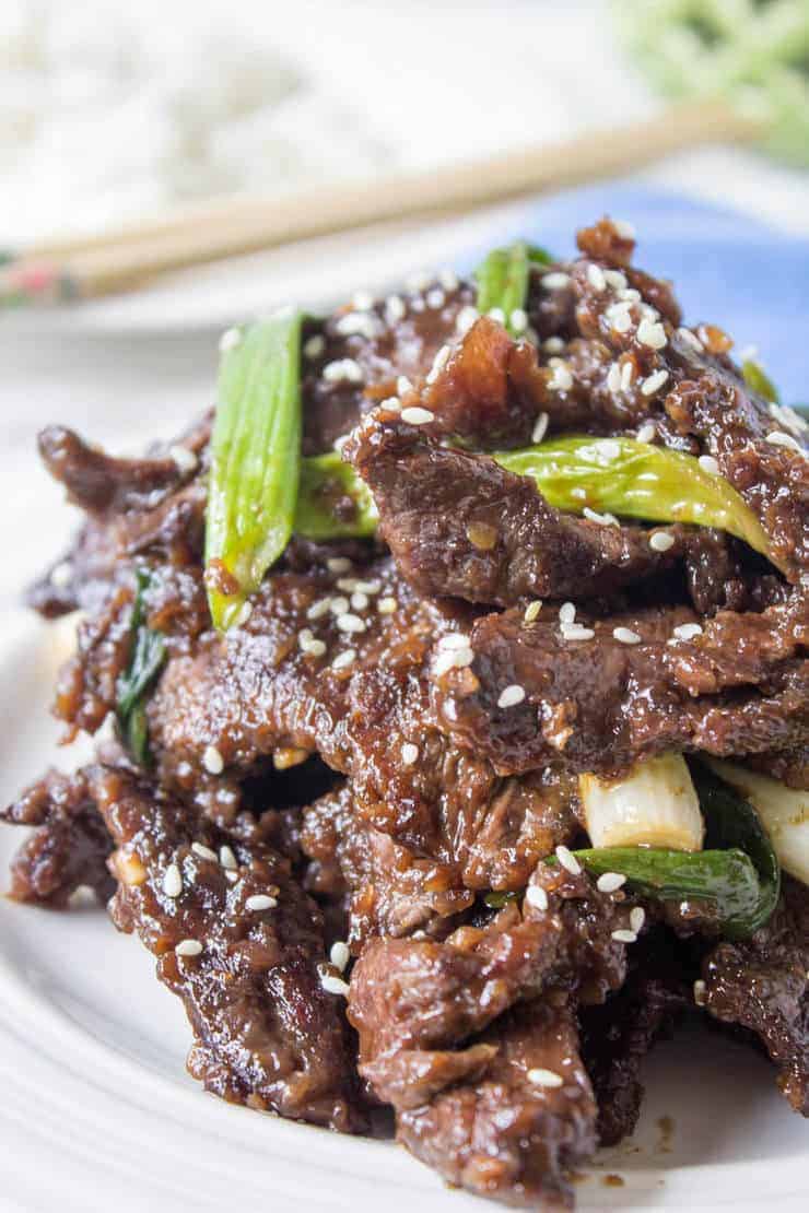 A plateful of Chinese food topped with green onions.