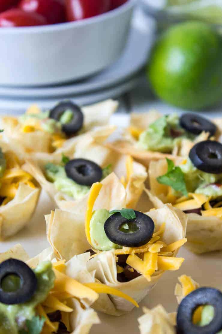 Mini taco cups filled with cheese and guacamole.