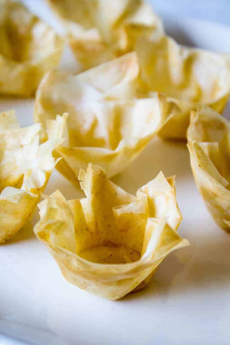 Phyllo cups without any filling arranged on a white platter.