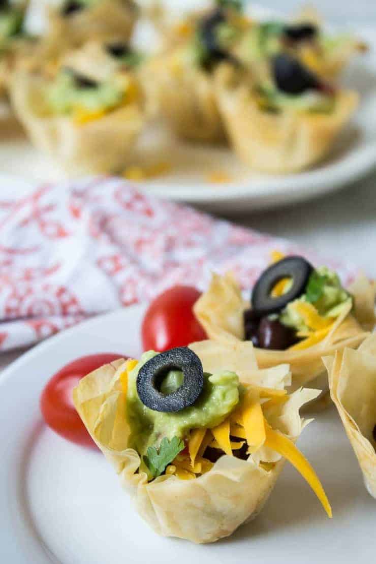 Mini tacos filled with cheese, guacamole and topped with a sliced black olive.