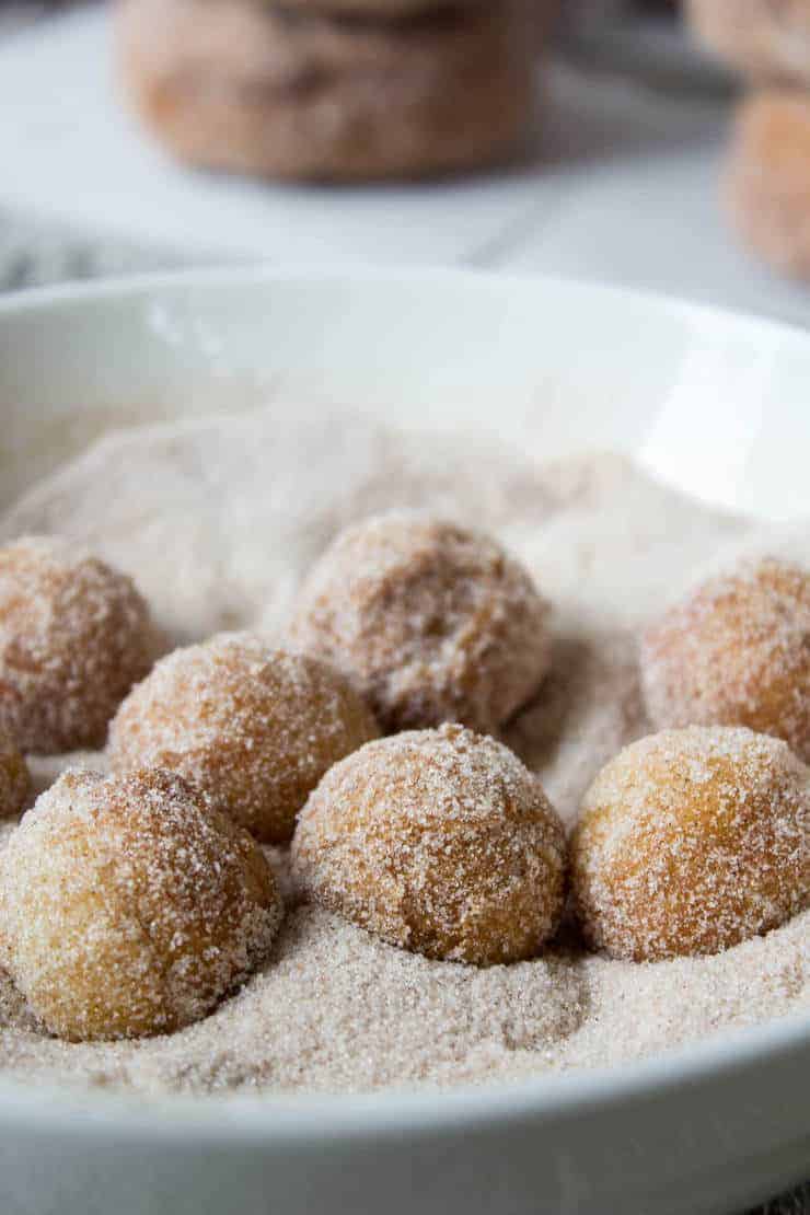 Doughnut holes in a bowl with sugar.