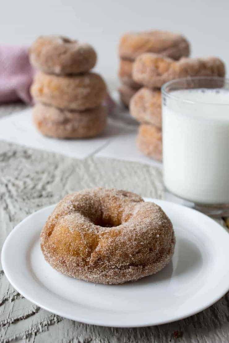 Cinnamon Sugar Cake Doughnut on a white plate with a glass of milk in the background. 