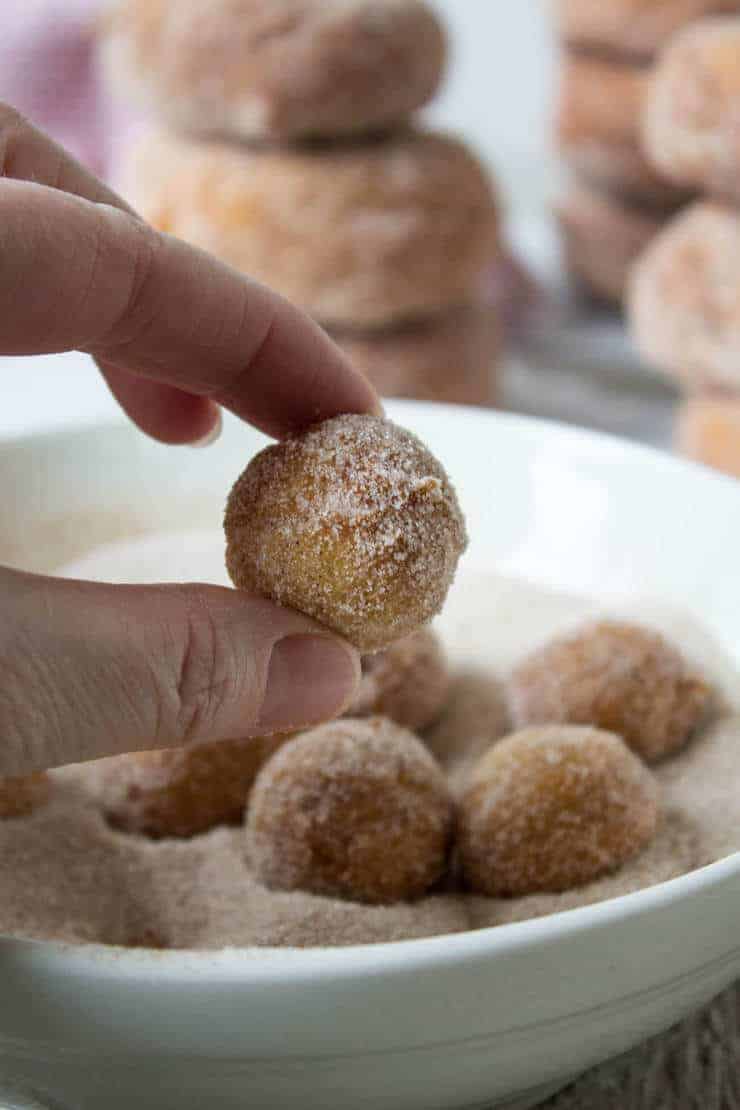 Two fingers holding a doughnut hole. 